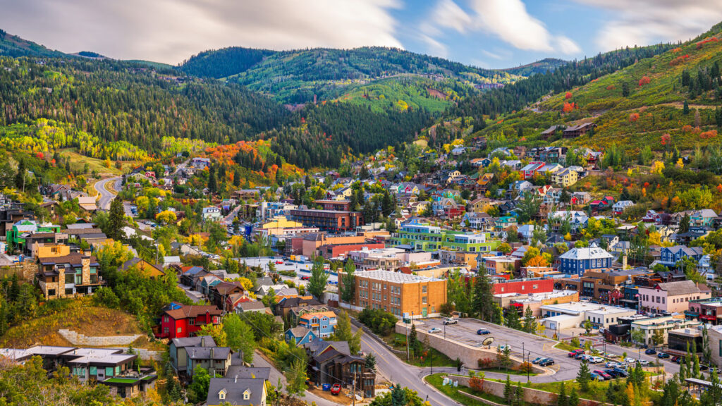 Scenic aerial view of downtown Park City, Utah, surrounded by vibrant fall foliage and mountain trails.