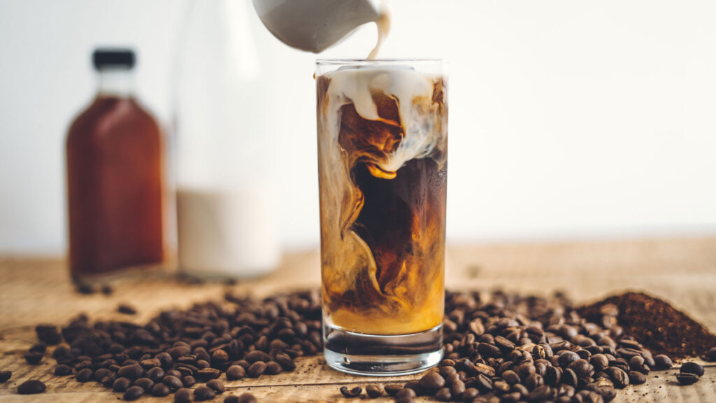 A glass of cold brew with loose roasted coffee beans from Cupla Coffee on a table